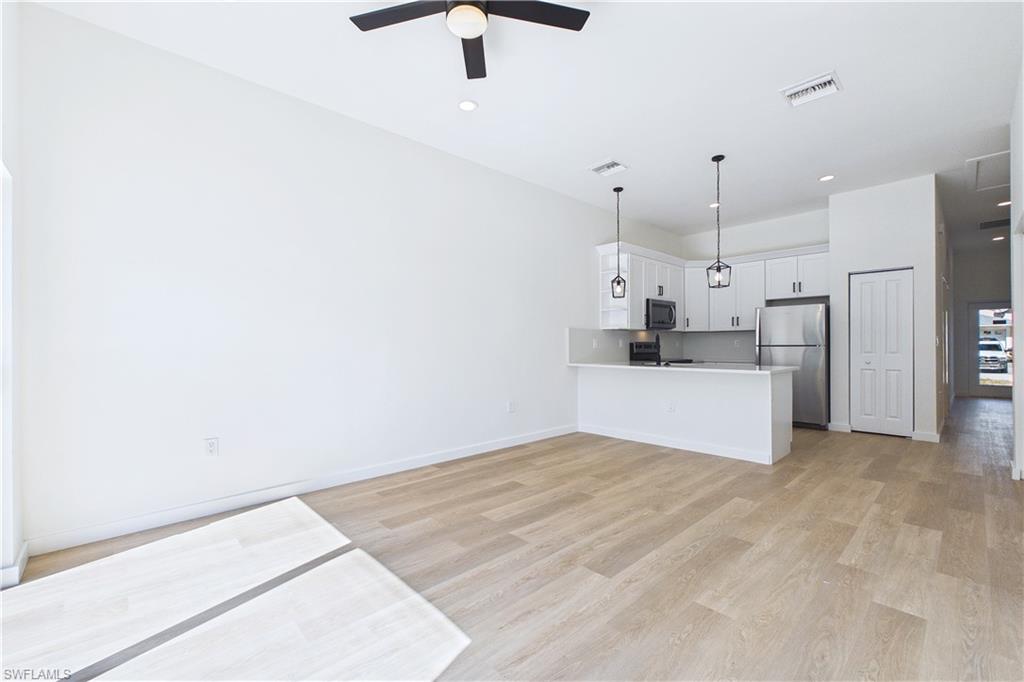 Kitchen with a peninsula, light countertops, stainless steel appliances, light wood-type flooring, and open floor plan