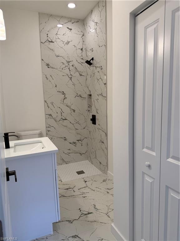 Bathroom with a marble finish shower, vanity, recessed lighting, and light marble finish floors