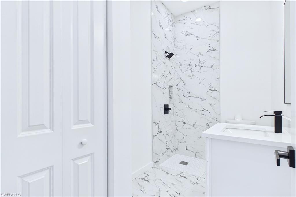 Full bath with a marble finish shower, vanity, and light marble finish flooring
