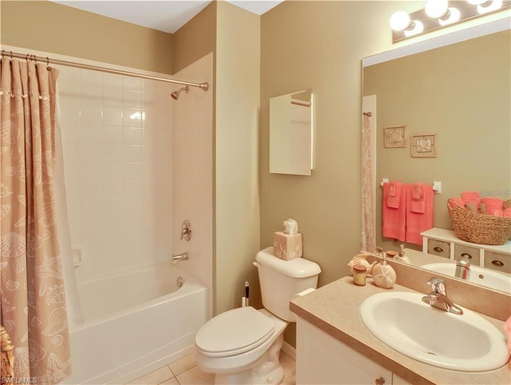 Full bathroom featuring shower / tub combo with curtain, vanity, and light tile patterned floors
