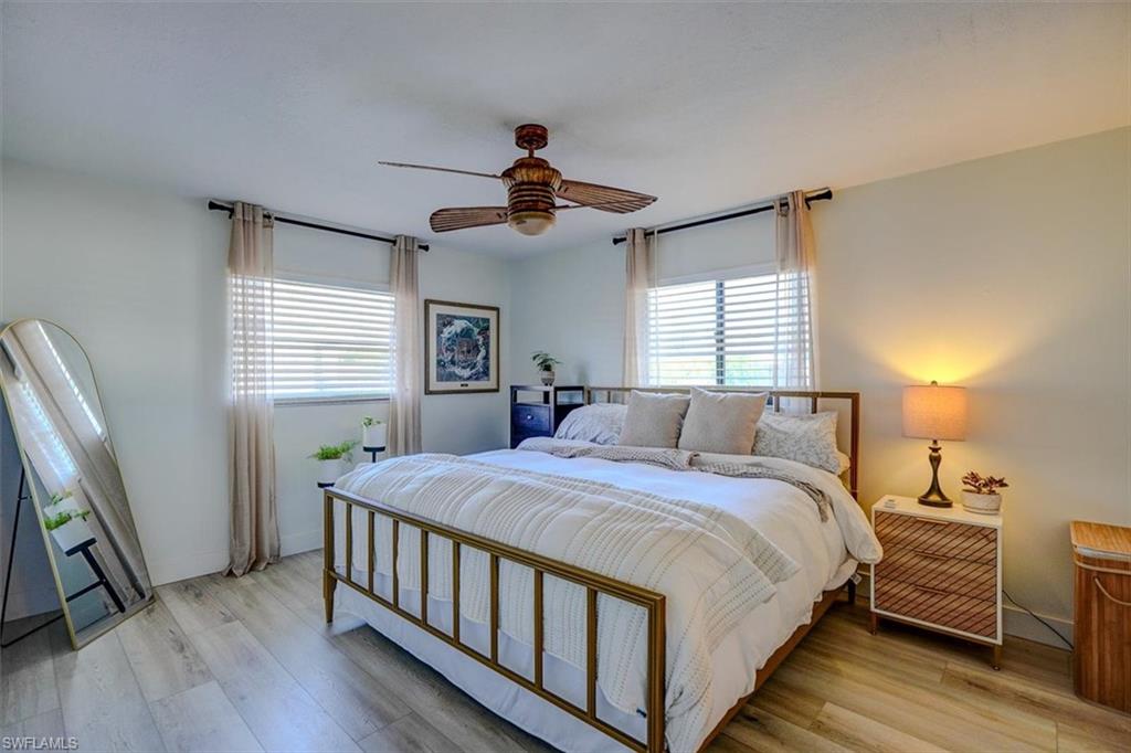 Bedroom with ceiling fan, light wood-type flooring, and multiple windows