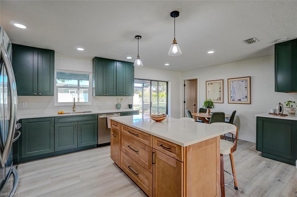 Kitchen featuring a center island, hanging light fixtures, sink, light wood-type flooring, and appliances with stainless steel finishes