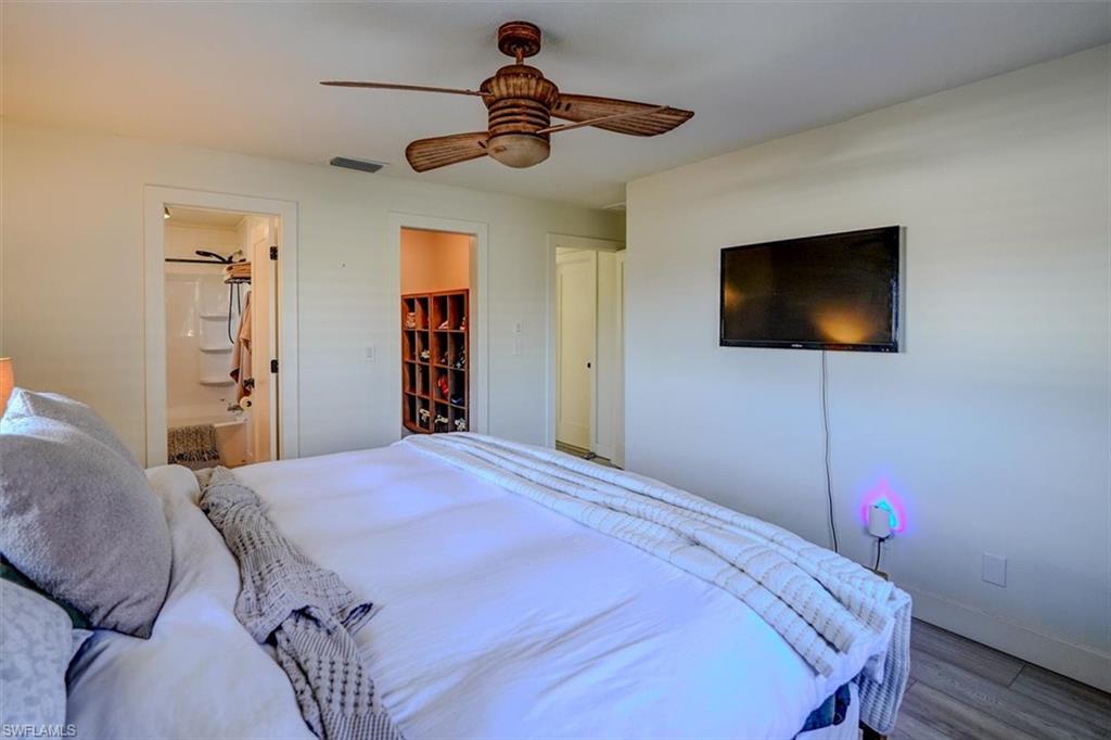 Bedroom featuring a walk in closet, ensuite bath, ceiling fan, light hardwood / wood-style flooring, and a closet