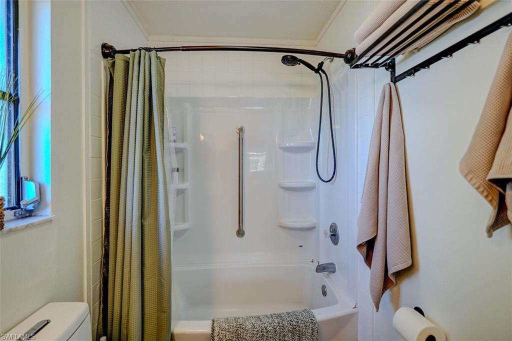 Bathroom with shower / bath combination with curtain and toilet