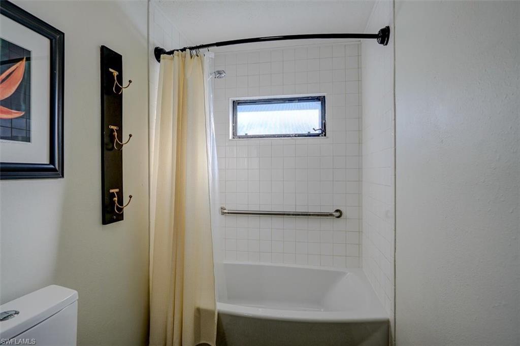 Bathroom featuring toilet and shower / bathtub combination with curtain