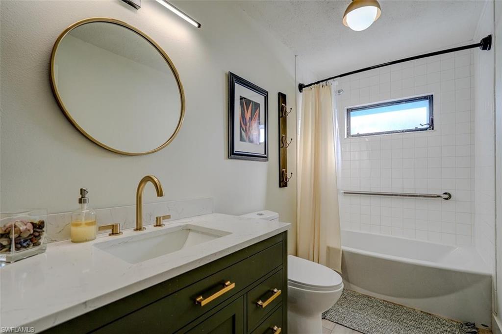 Full bathroom with vanity, tile patterned flooring, toilet, a textured ceiling, and shower / tub combo with curtain