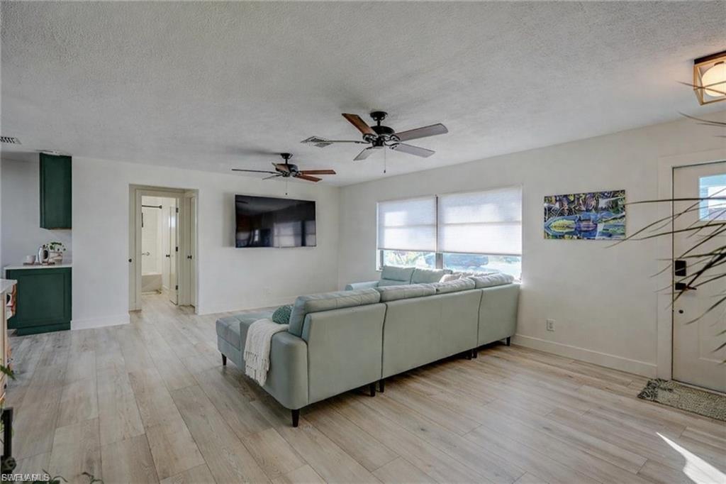Living area with a textured ceiling, light wood finished floors, and a ceiling fan