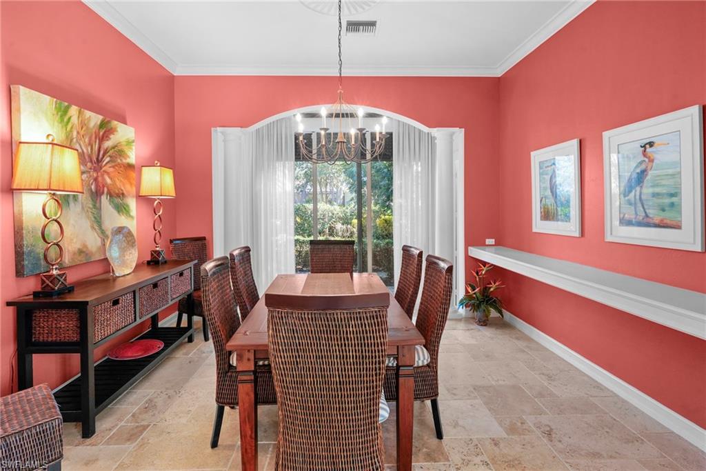 Dining room with stone tile flooring, hanging lights, and crown molding