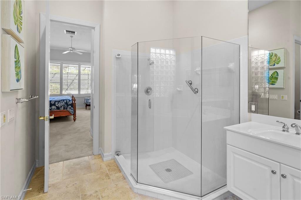 Ensuite bathroom featuring a shower stall, vanity, and ceiling fan