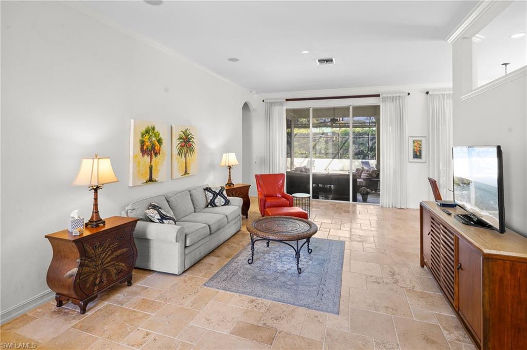 Living area featuring stone tile floors, arched walkways, and crown molding