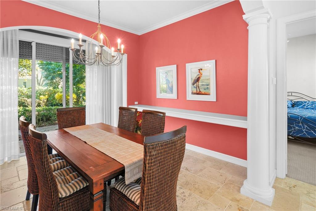 Dining area with decorative columns, stone tile floors, ornamental molding, and suspended lighting