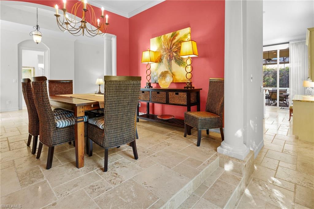 Dining space featuring stone tile flooring, a chandelier, crown molding, and arched walkways