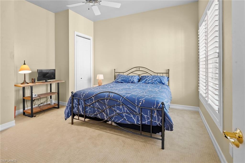 Carpeted bedroom with ceiling fan and a closet