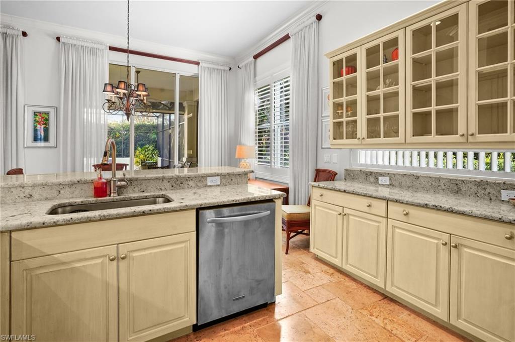 Kitchen featuring light stone counters, dishwasher, cream cabinets, suspended lighting, and stone tile flooring