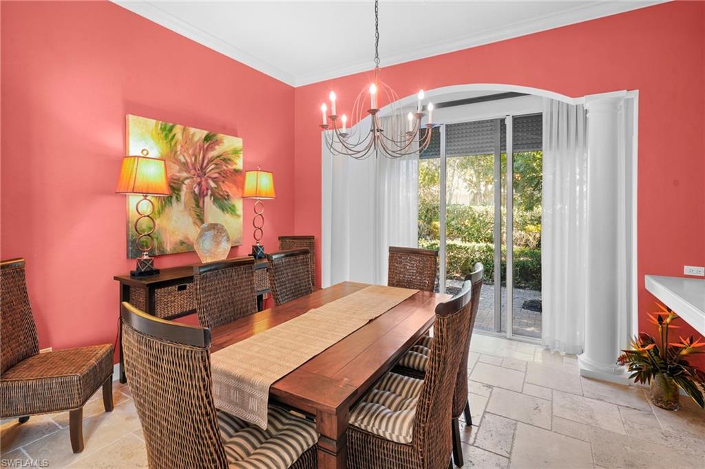 Dining room with stone tile floors, ornamental molding, and hanging lights