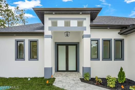 Entrance to property featuring stucco siding and a shingled roof