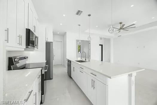 Kitchen with stainless steel appliances, white cabinetry, finished concrete floors, and an island with sink