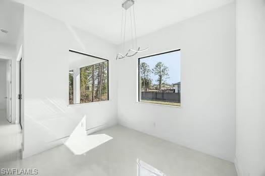 Unfurnished dining area with concrete floors and a chandelier