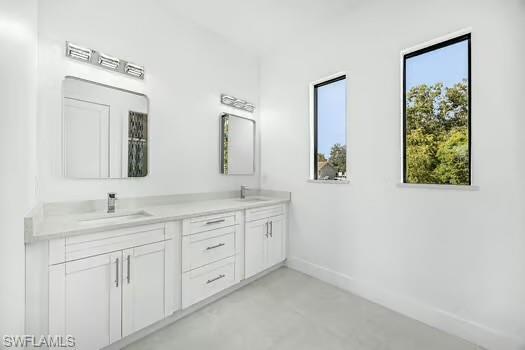 Full bath featuring double vanity and finished concrete floors