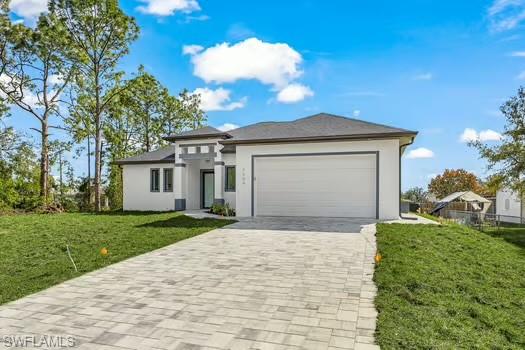 Prairie-style house featuring a front lawn, decorative driveway, a garage, and stucco siding
