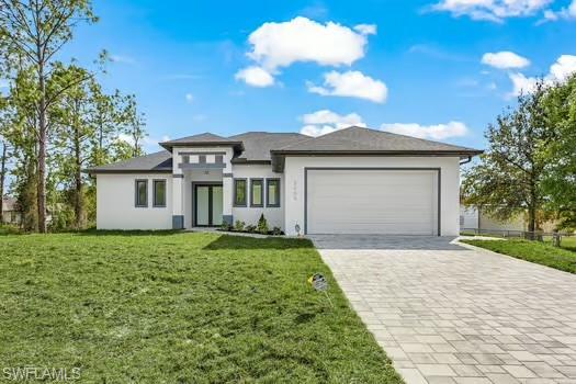 Prairie-style home with decorative driveway, stucco siding, a front yard, and a garage