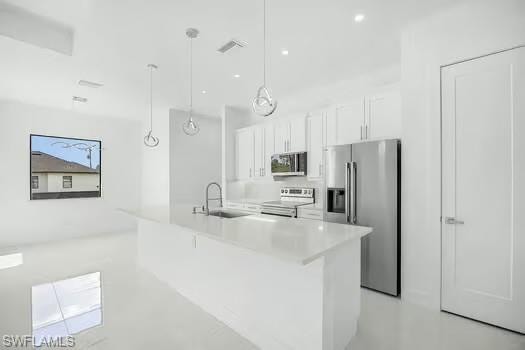 Kitchen with stainless steel appliances, white cabinets, pendant lighting, an island with sink, and finished concrete flooring