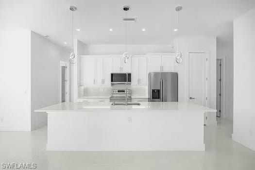 Kitchen with white cabinets, stainless steel appliances, a spacious island, hanging light fixtures, and light stone countertops