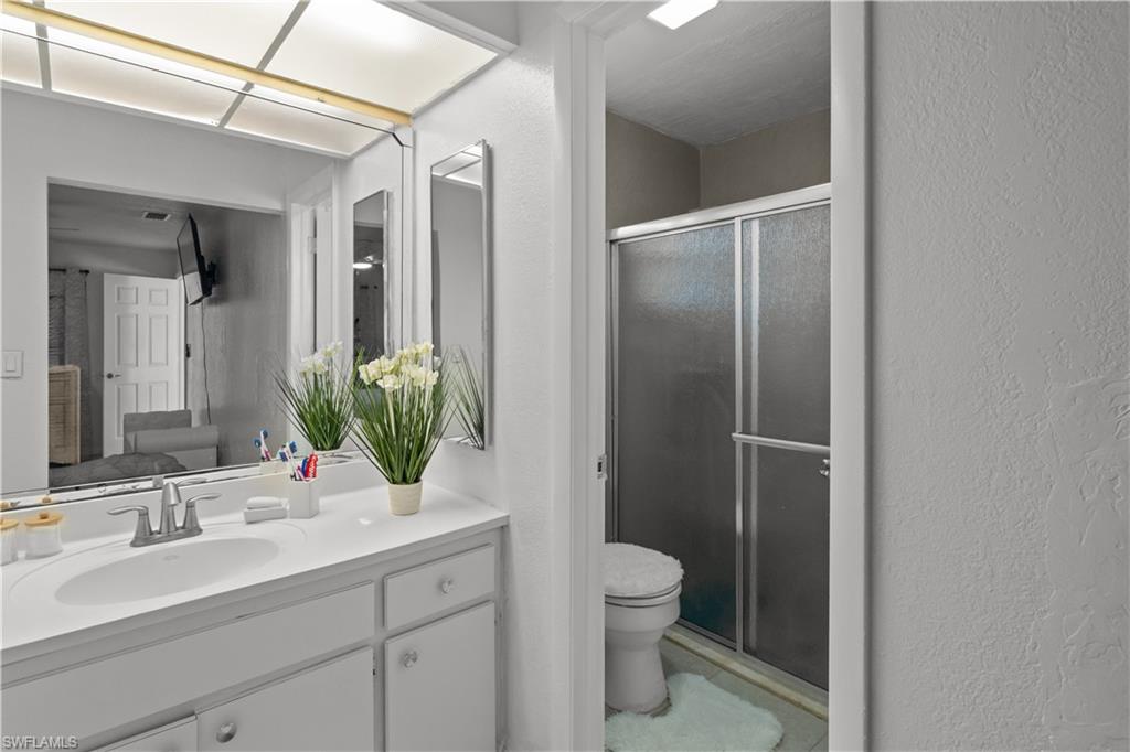 Bathroom featuring a textured wall, vanity, and a stall shower