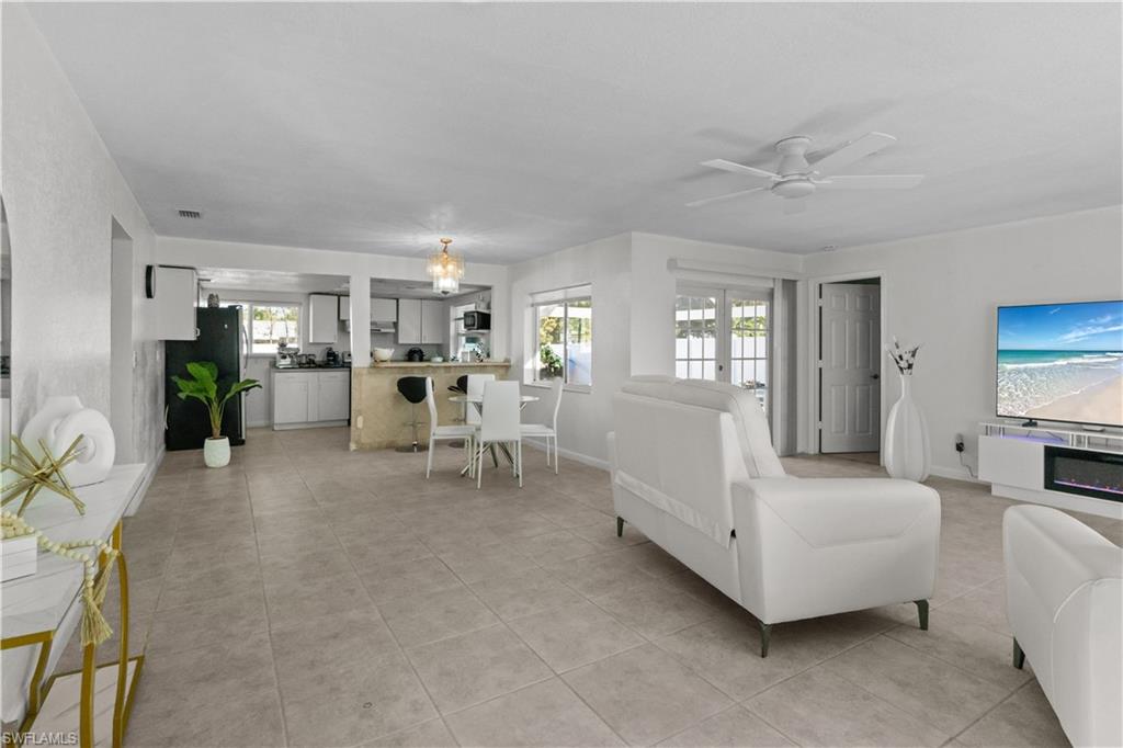 Living room featuring a ceiling fan, light tile patterned floors, and french doors