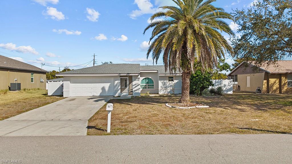 Single story home featuring concrete driveway, a front yard, an attached garage, and stucco siding