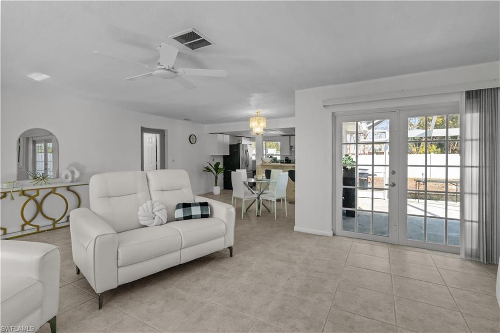 Living area with ceiling fan, french doors, and light tile patterned floors