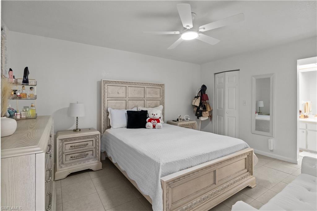 Bedroom with a closet, ceiling fan, light tile patterned flooring, and ensuite bathroom