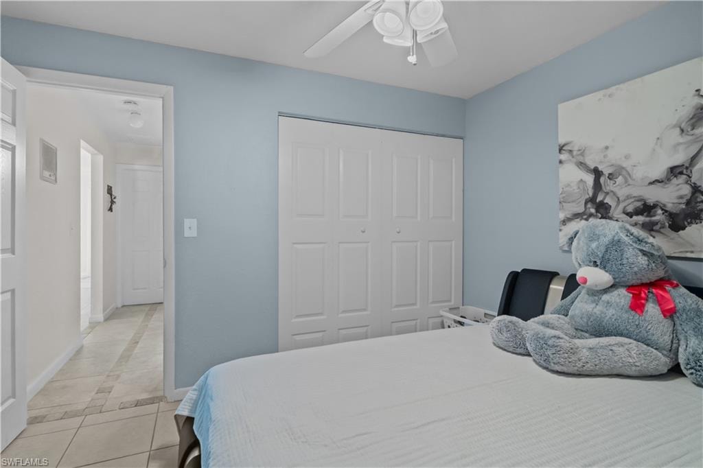 Bedroom with light tile patterned floors, a closet, ceiling fan, and inlaid floor details