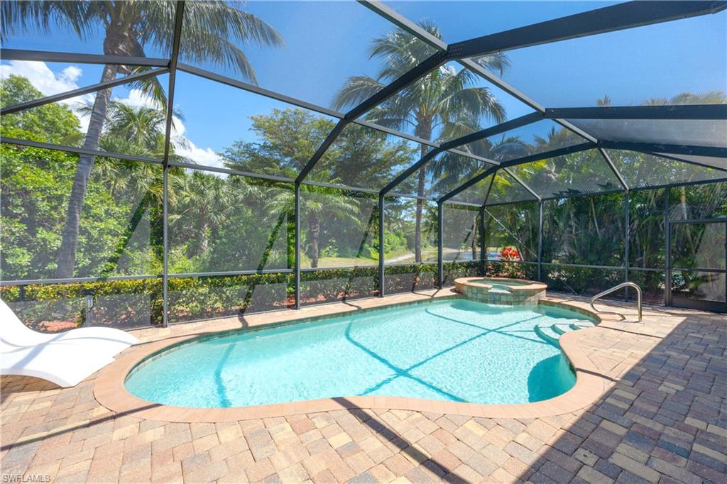 View of swimming pool with a pool with connected hot tub, a lanai, and a patio area