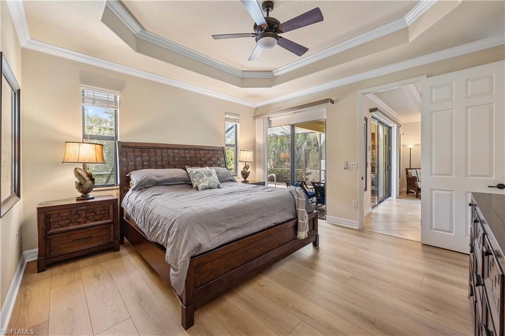Bedroom featuring multiple windows, light wood-style flooring, and a raised ceiling