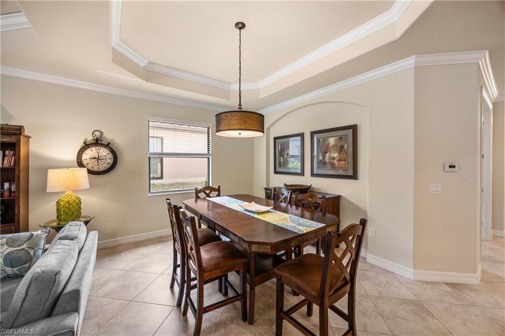 Dining space featuring baseboards, a tray ceiling, crown molding, and light tile patterned floors