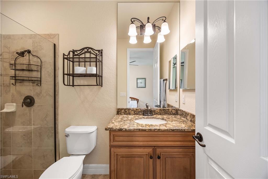 Full bathroom # 3with an inviting chandelier, toilet, vanity, and a tile shower