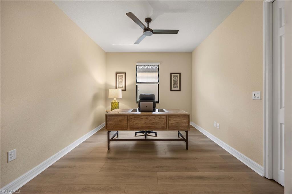 Office space featuring baseboards, wood finished floors, and a ceiling fan