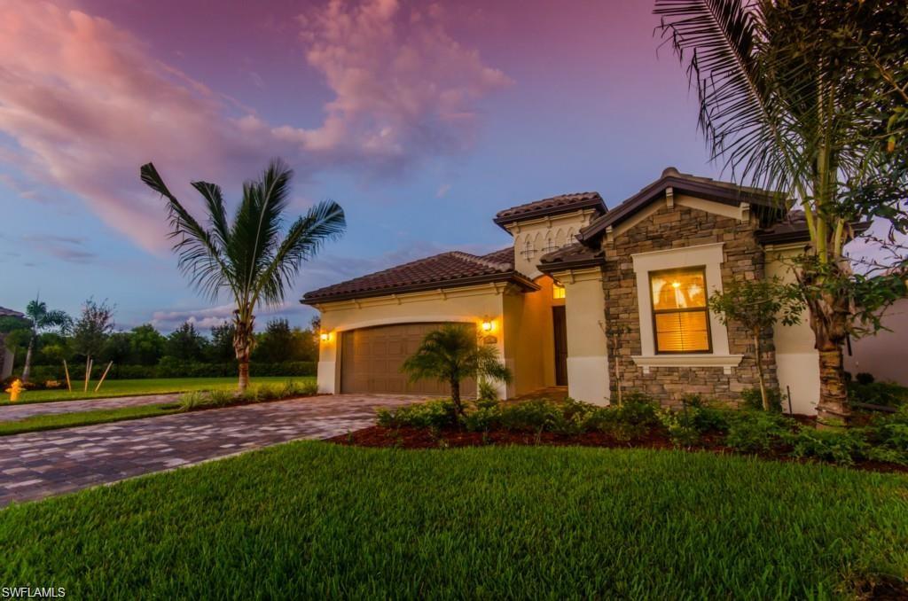Mediterranean / spanish house with a garage, a front yard, driveway, and stone siding