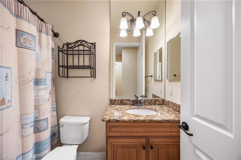 Bathroom # 2 featuring a shower with curtain, a textured wall, toilet, and vanity