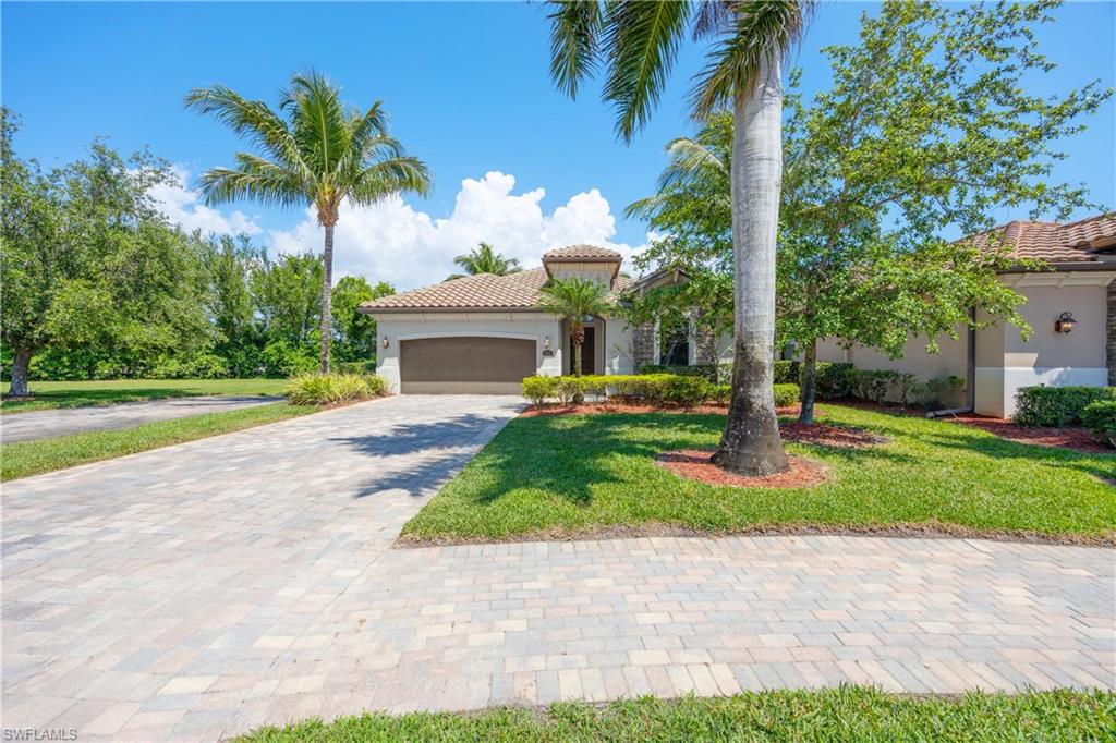 Mediterranean / spanish-style house with a tile roof, stucco siding, a front lawn, decorative driveway, and a garage