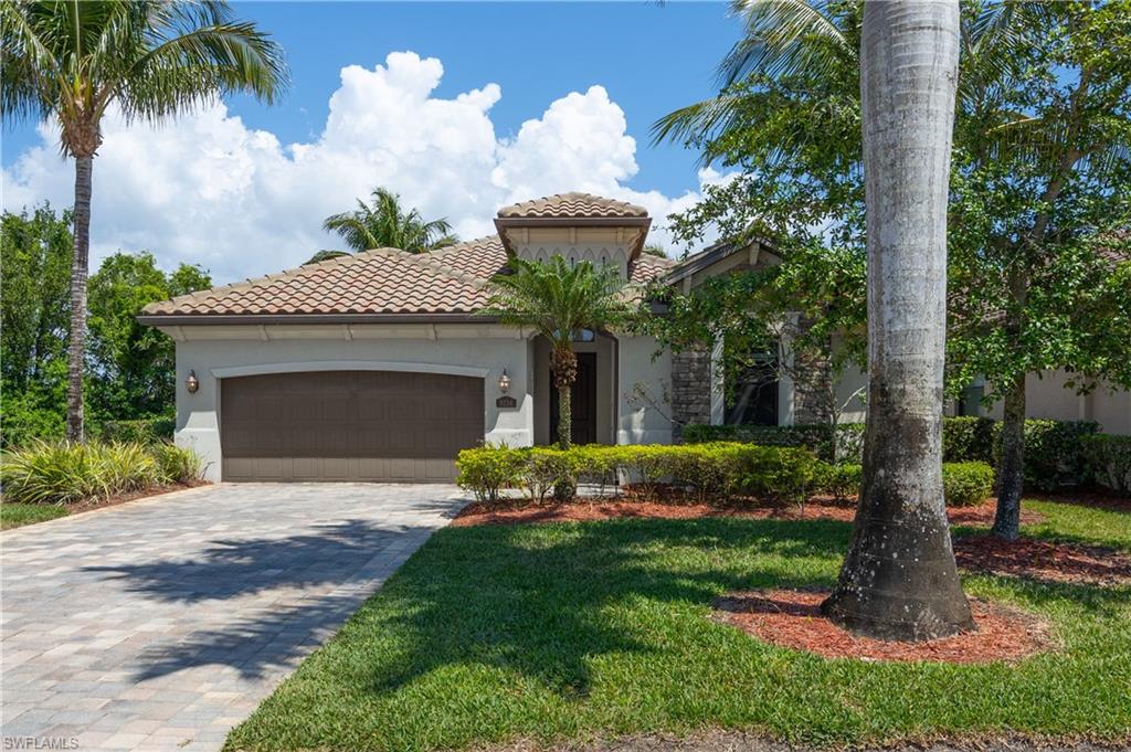 Mediterranean / spanish-style house with a tile roof, stucco siding, an attached garage, decorative driveway, and a front lawn