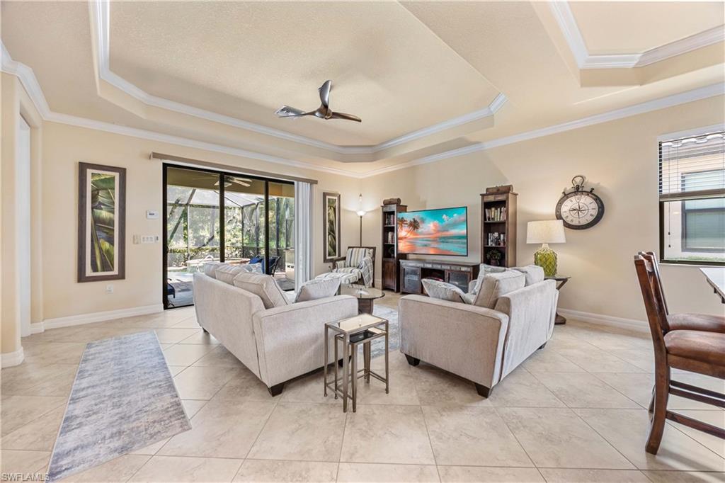 Living room featuring a tray ceiling, a wealth of natural light, crown molding, and baseboards