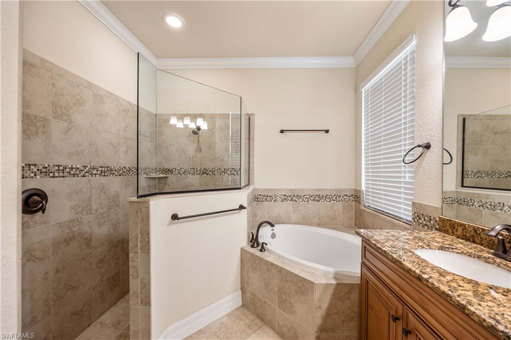 Full bath with vanity, ornamental molding, a garden tub, and a walk in shower