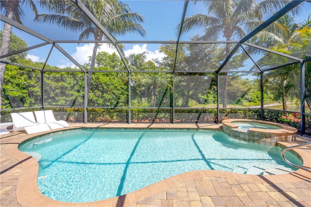 View of swimming pool featuring a pool with connected hot tub, glass enclosure, and a patio