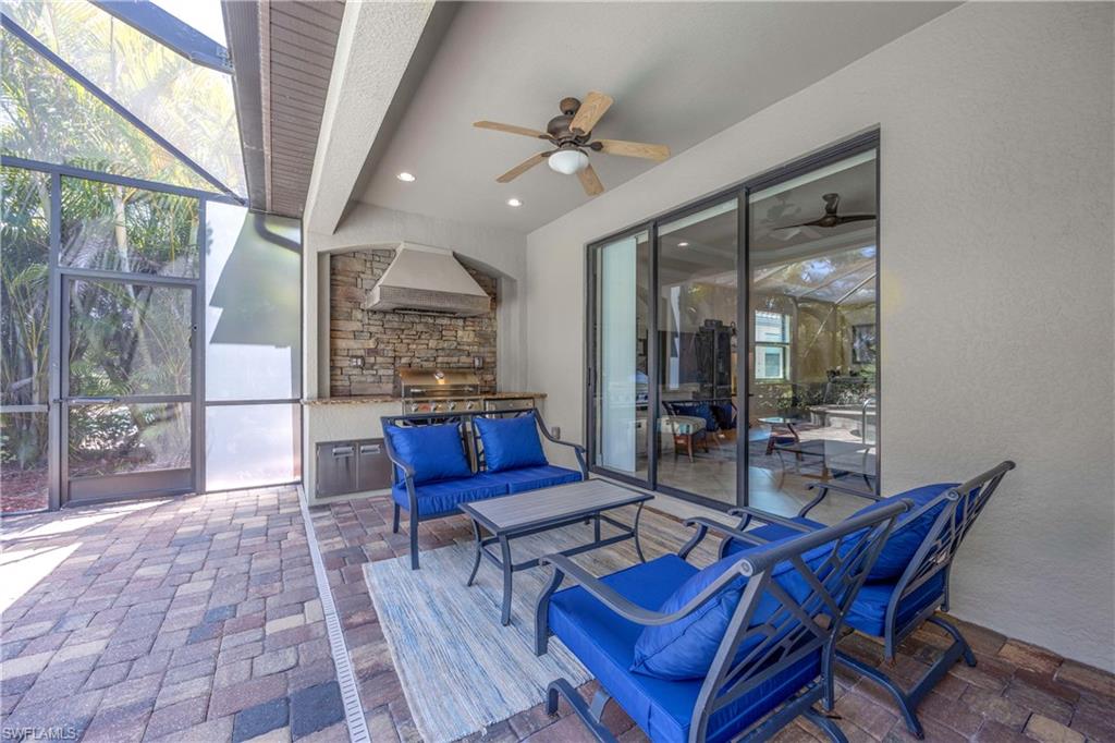 View of patio featuring a lanai, a grill, exterior kitchen, an outdoor living space, and a ceiling fan