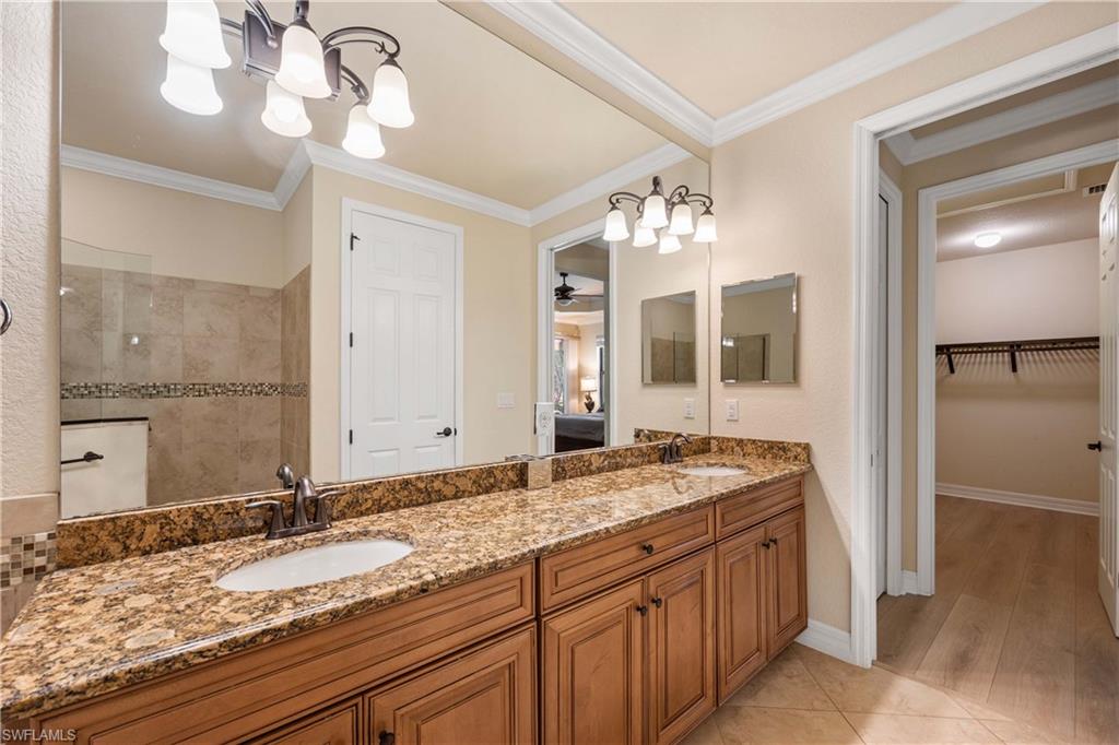 Bathroom featuring double vanity, ornamental molding, a sink, and a walk in shower