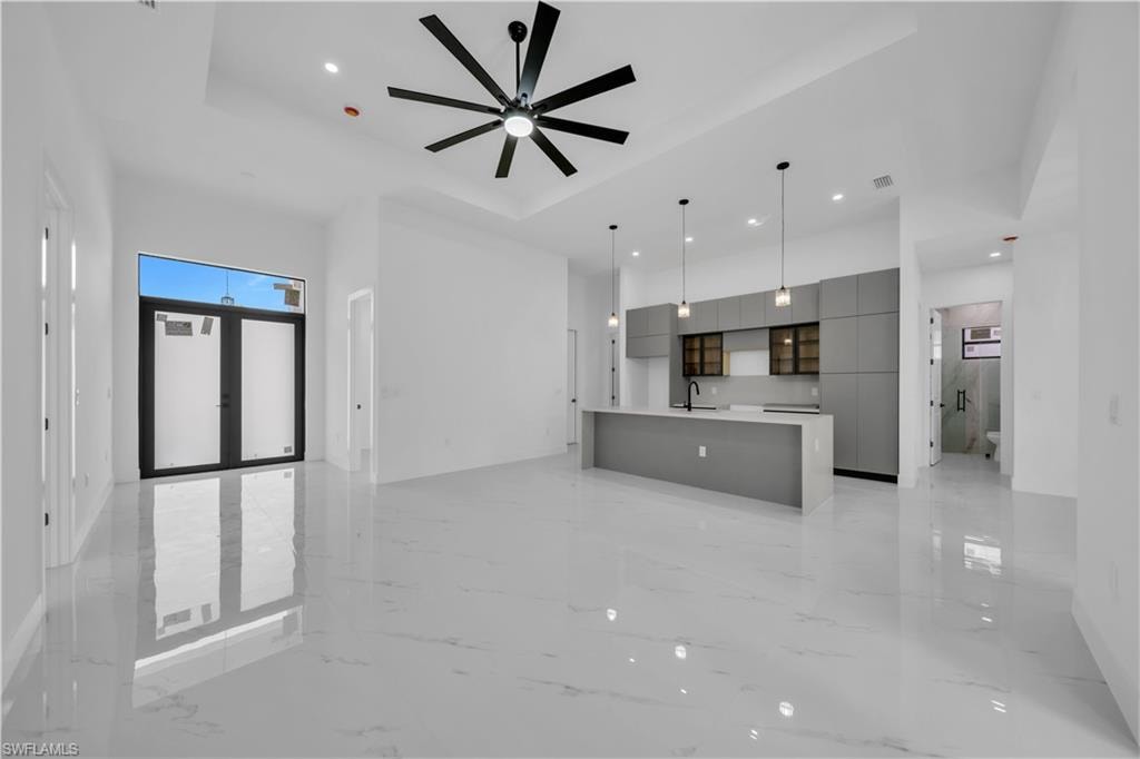 Unfurnished living room with light marble finish floors, recessed lighting, ceiling fan, and a raised ceiling