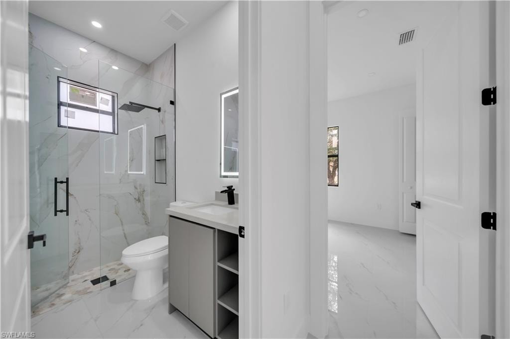 Full bath with light marble finish floors, vanity, a marble finish shower, and recessed lighting