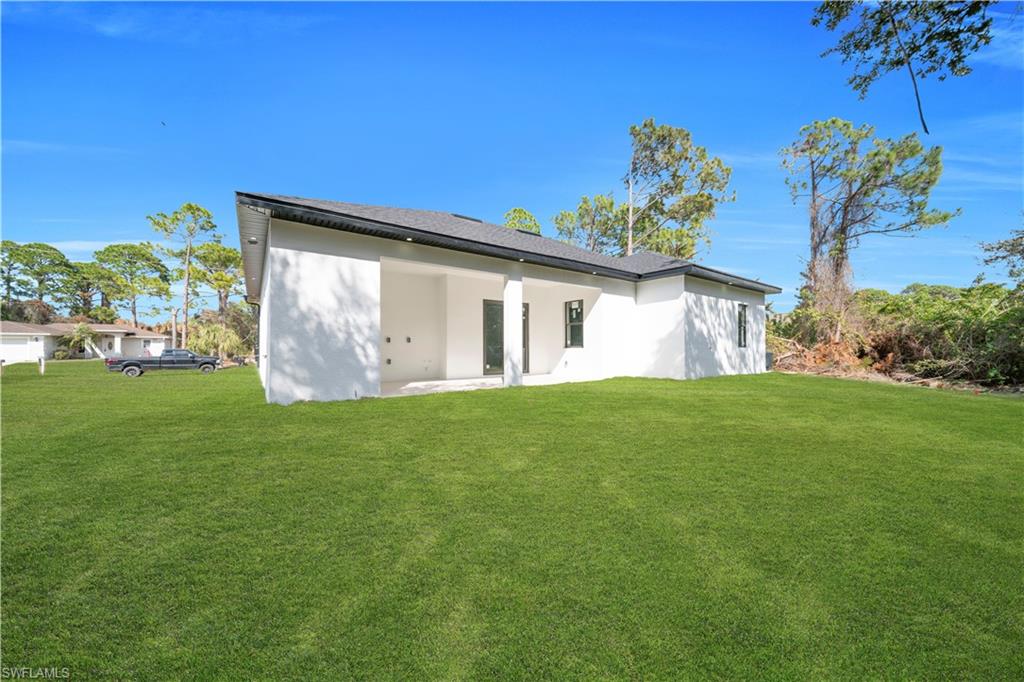 Rear view of house with a lawn, a patio area, and stucco siding
